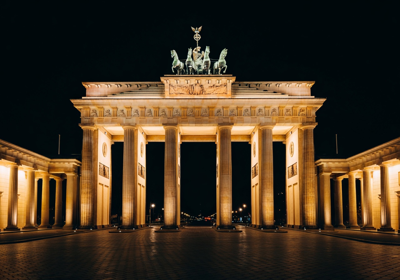 Brandenburg Gate illuminated at night in Berlin with golden light reflecting on the stone columns